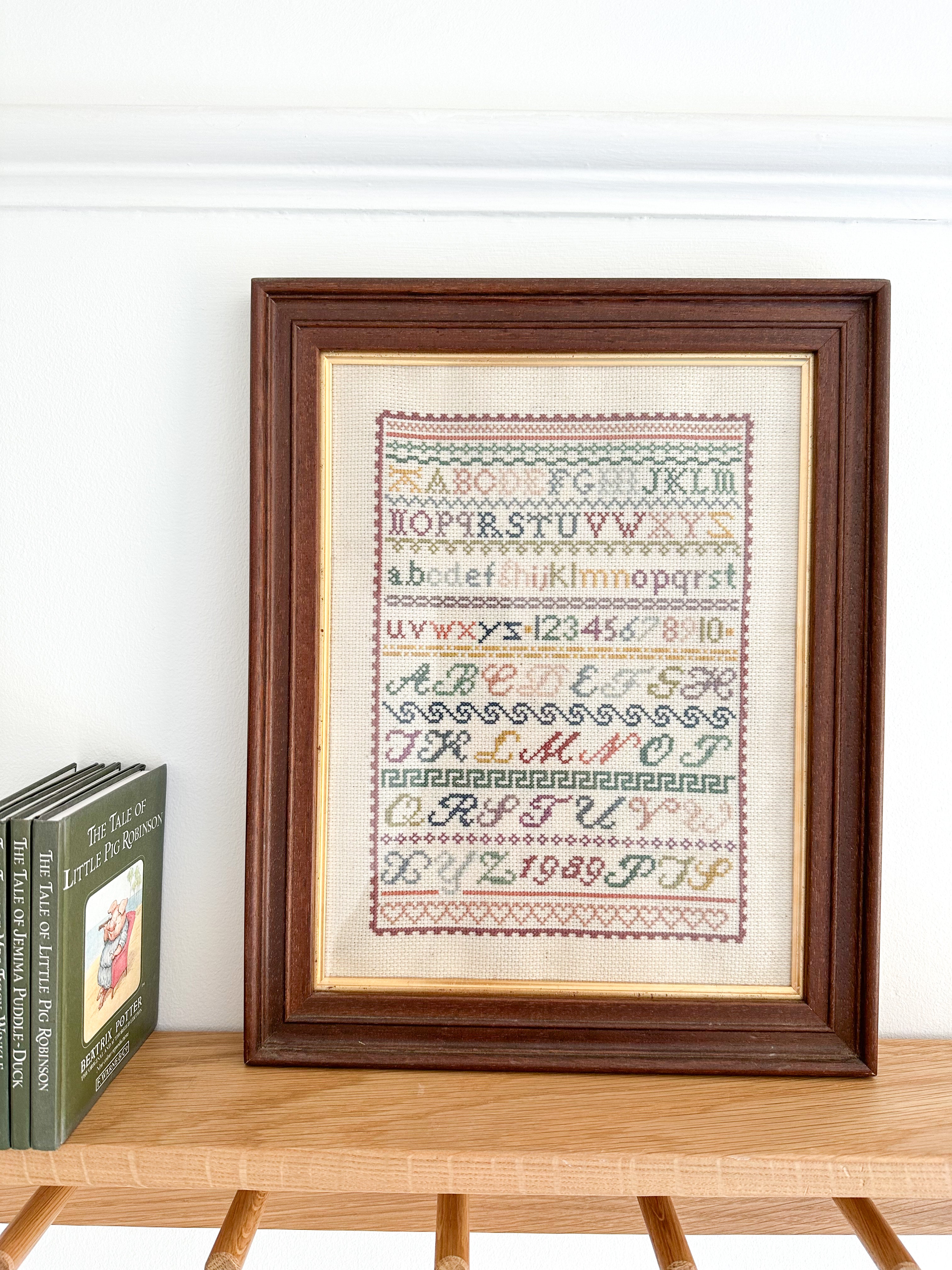 Vintage framed alphabet cross stitch embroidery sampler, in muted blue, pink, green and yellow - Moppet