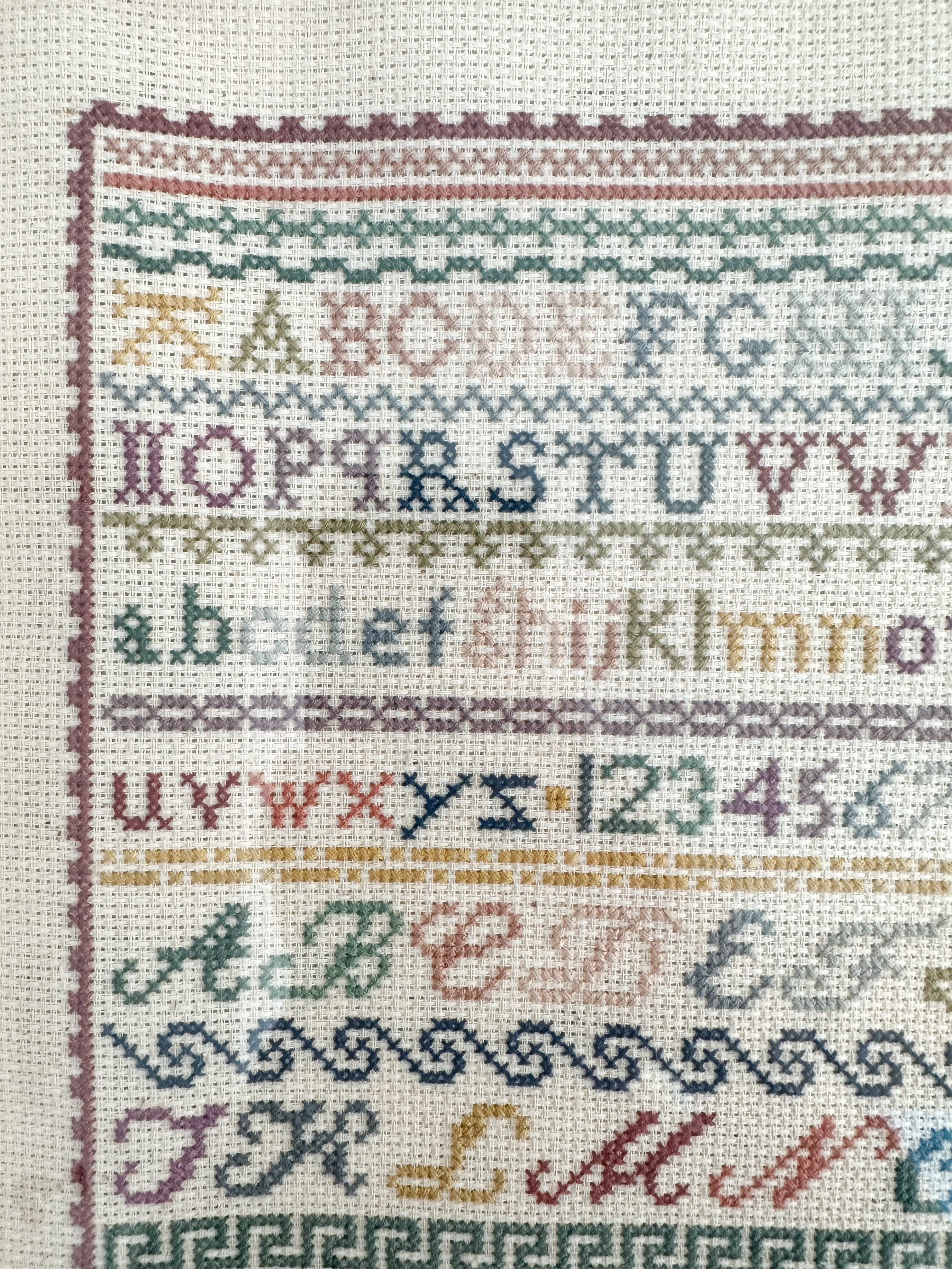 Vintage framed alphabet cross stitch embroidery sampler, in muted blue, pink, green and yellow - Moppet