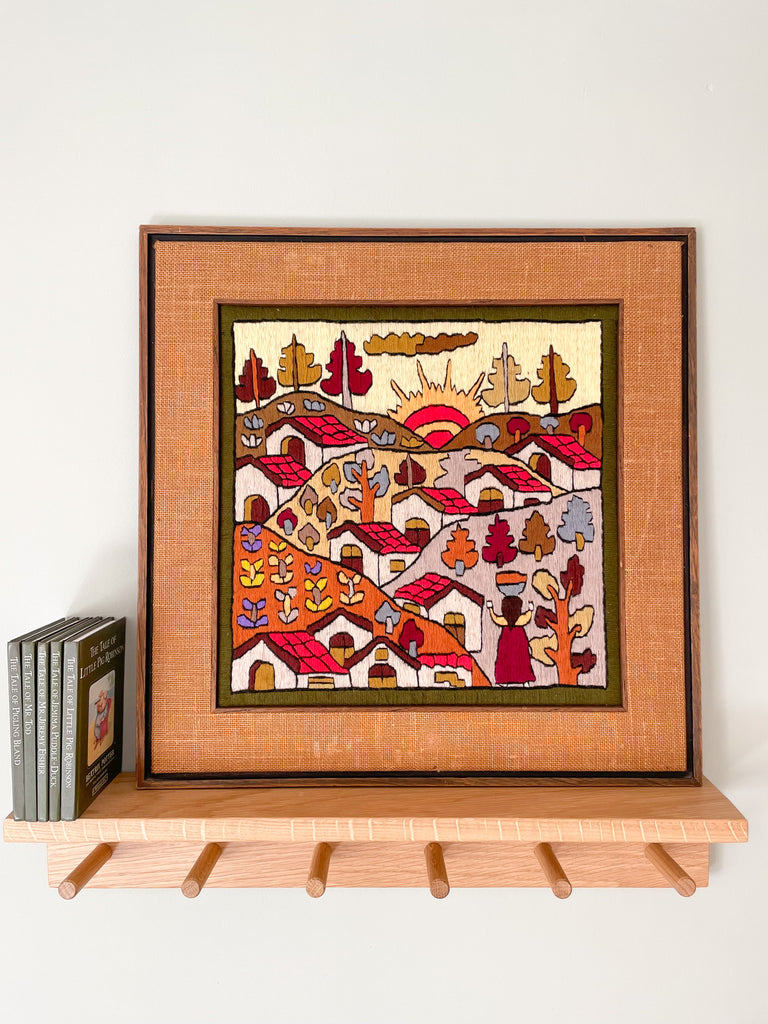 Vintage framed folk art woollen embroidery featuring a sun rising over a village in earthy autumnal colours - Moppet