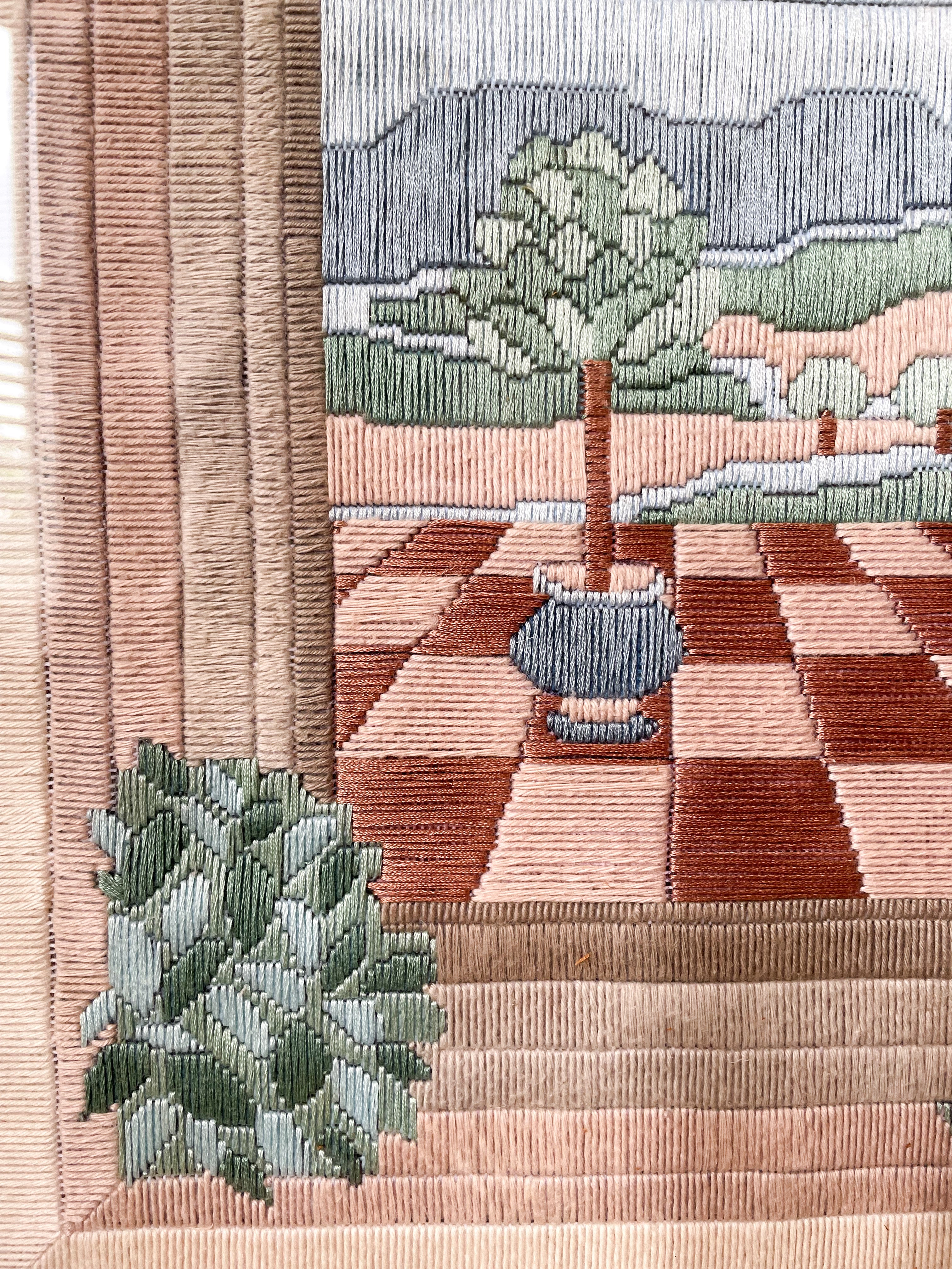 Vintage framed embroidery of a potted tree on a checkerboard patio - Moppet