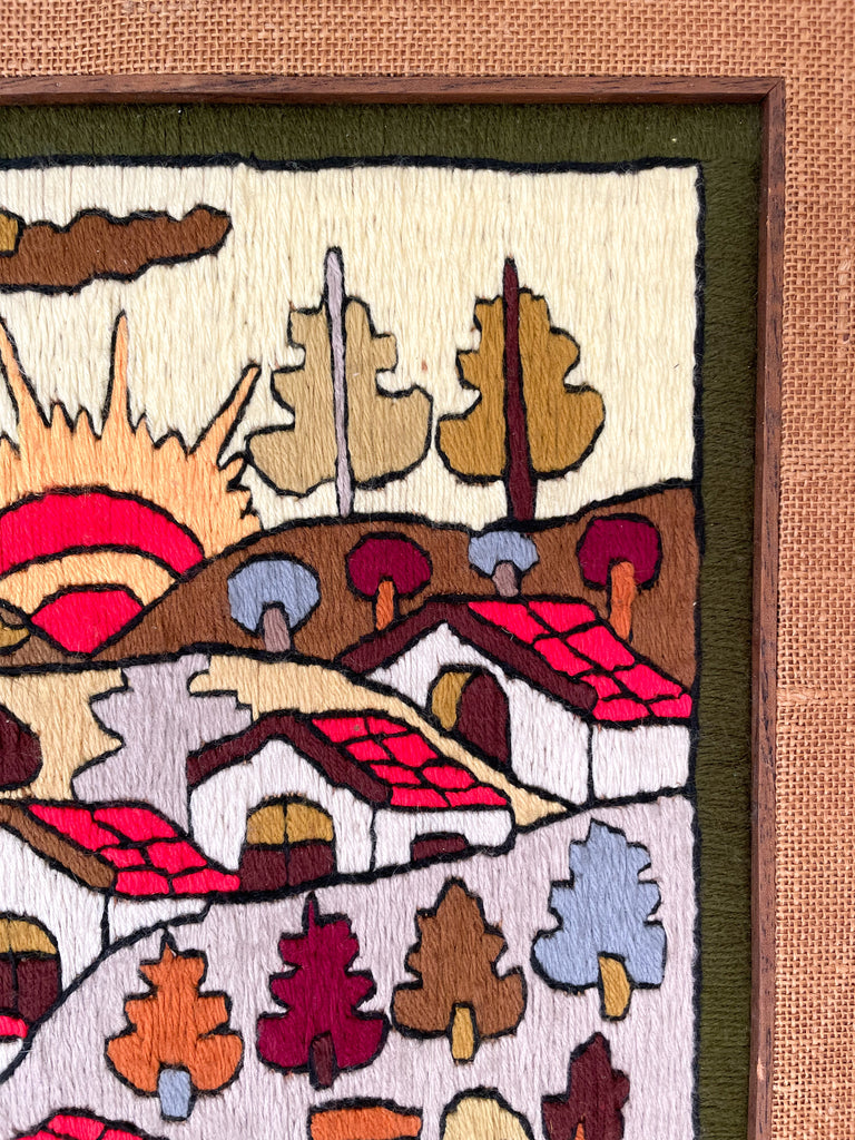 Vintage framed folk art woollen embroidery featuring a sun rising over a village in earthy autumnal colours - Moppet